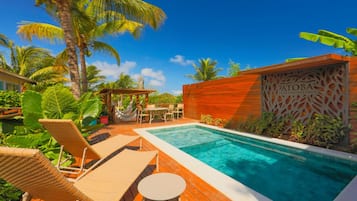 Ein Poolbereich mit Liegestühlen, einer Holzterrasse und einer Holzwand mit dekorativem Muster.