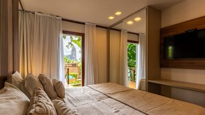 A bedroom with a bed, curtains, a TV, and a view of a balcony. - Pousada Atobá (Fernando de Noronha)