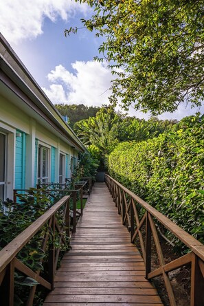 A wooden pathway leading to a building with turquoise shutters. - Pousada Atobá (Fernando de Noronha)