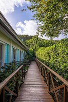 A wooden pathway leading to a building with turquoise shutters.