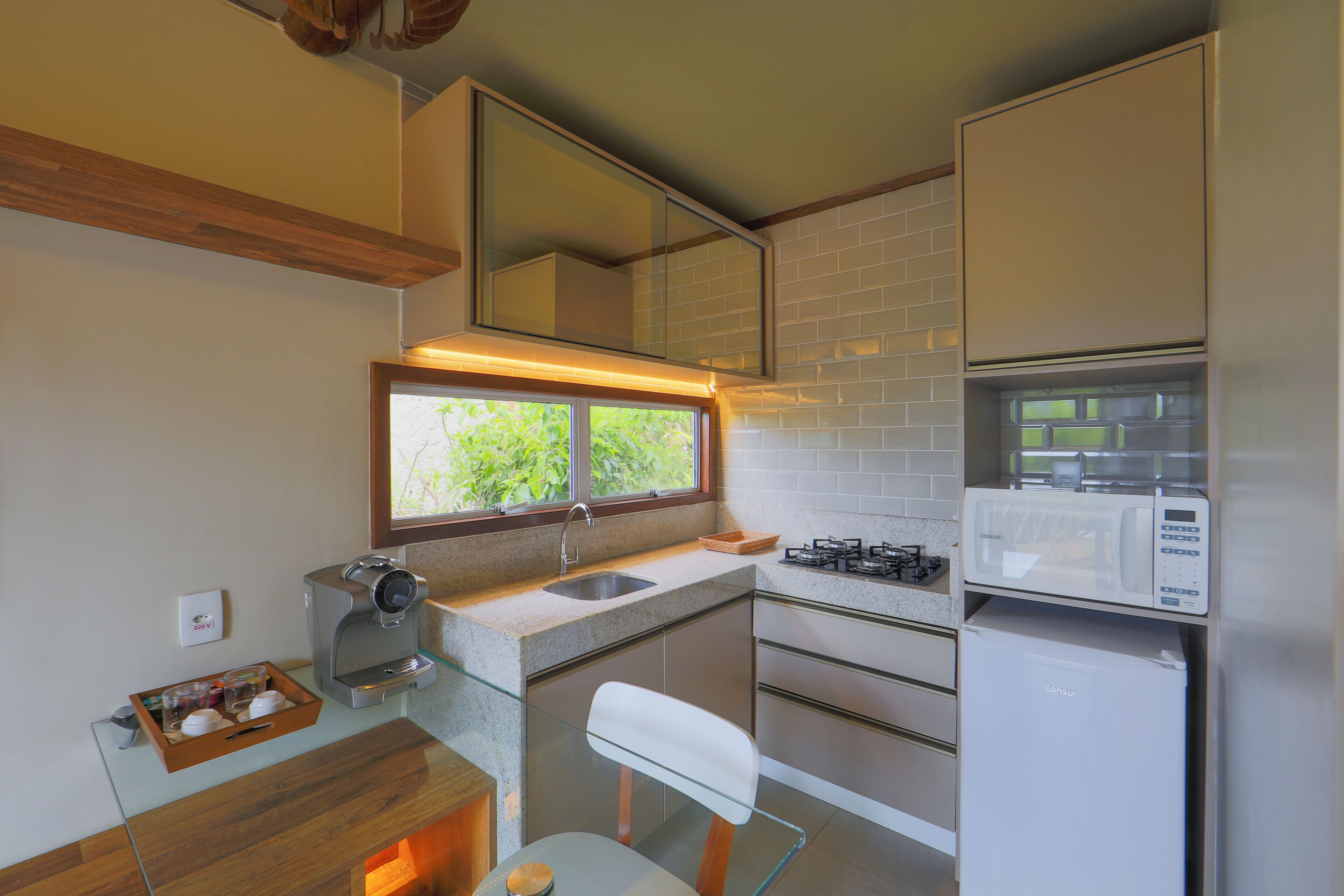 A compact kitchen with a coffee machine, a microwave, and a refrigerator.