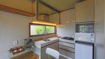 A compact kitchen with a coffee machine, a microwave, and a refrigerator.