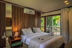 A hotel room with a bed, bedside table, lamp, and an air conditioning unit.