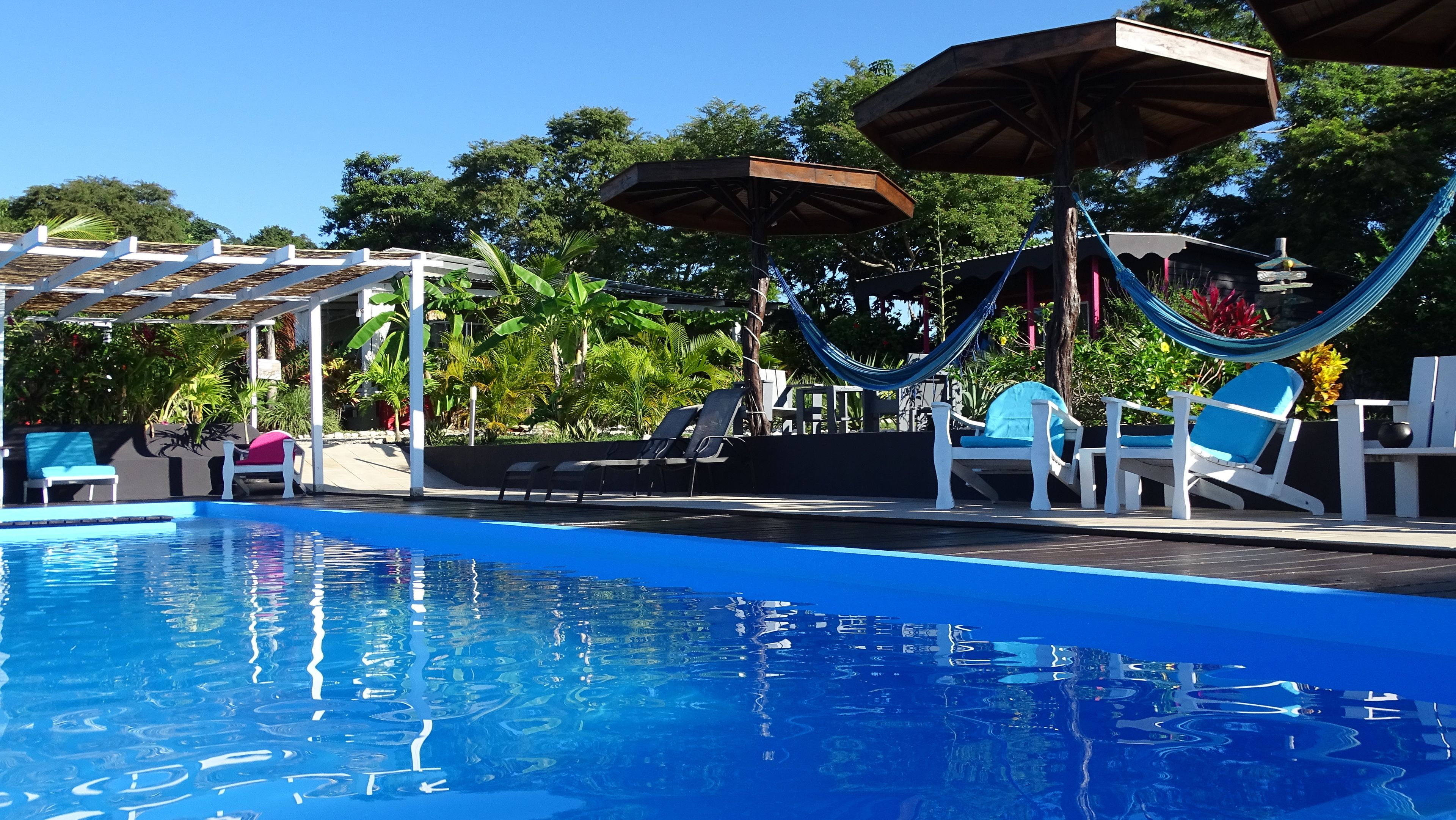 A clear blue pool with lounge chairs and umbrellas.