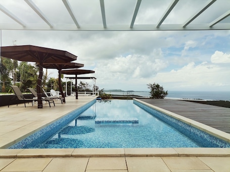 Una piscina al aire libre, una piscina infinita, sombrillas
