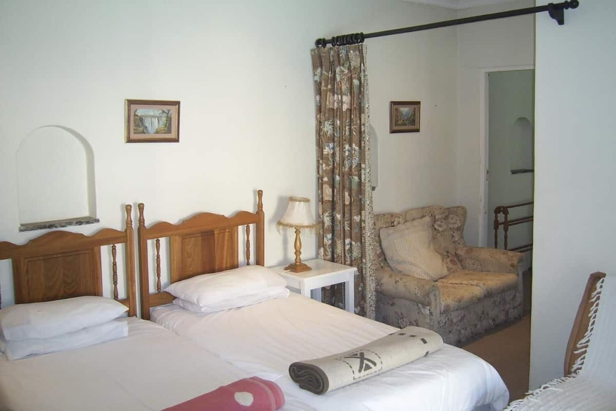 Une chambre à coucher avec un lit en bois, une chaise et une petite table avec une lampe.