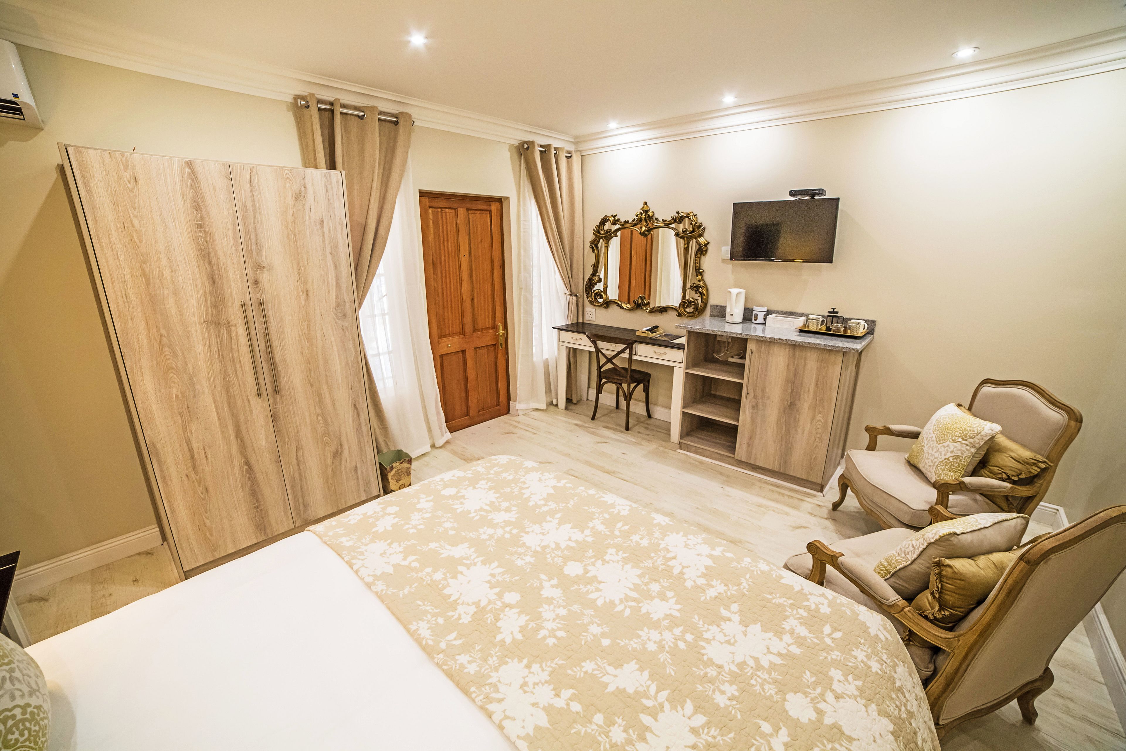 Ein Schlafzimmer mit Bett, Schreibtisch, Stuhl, Fernseher und Kleiderschrank.