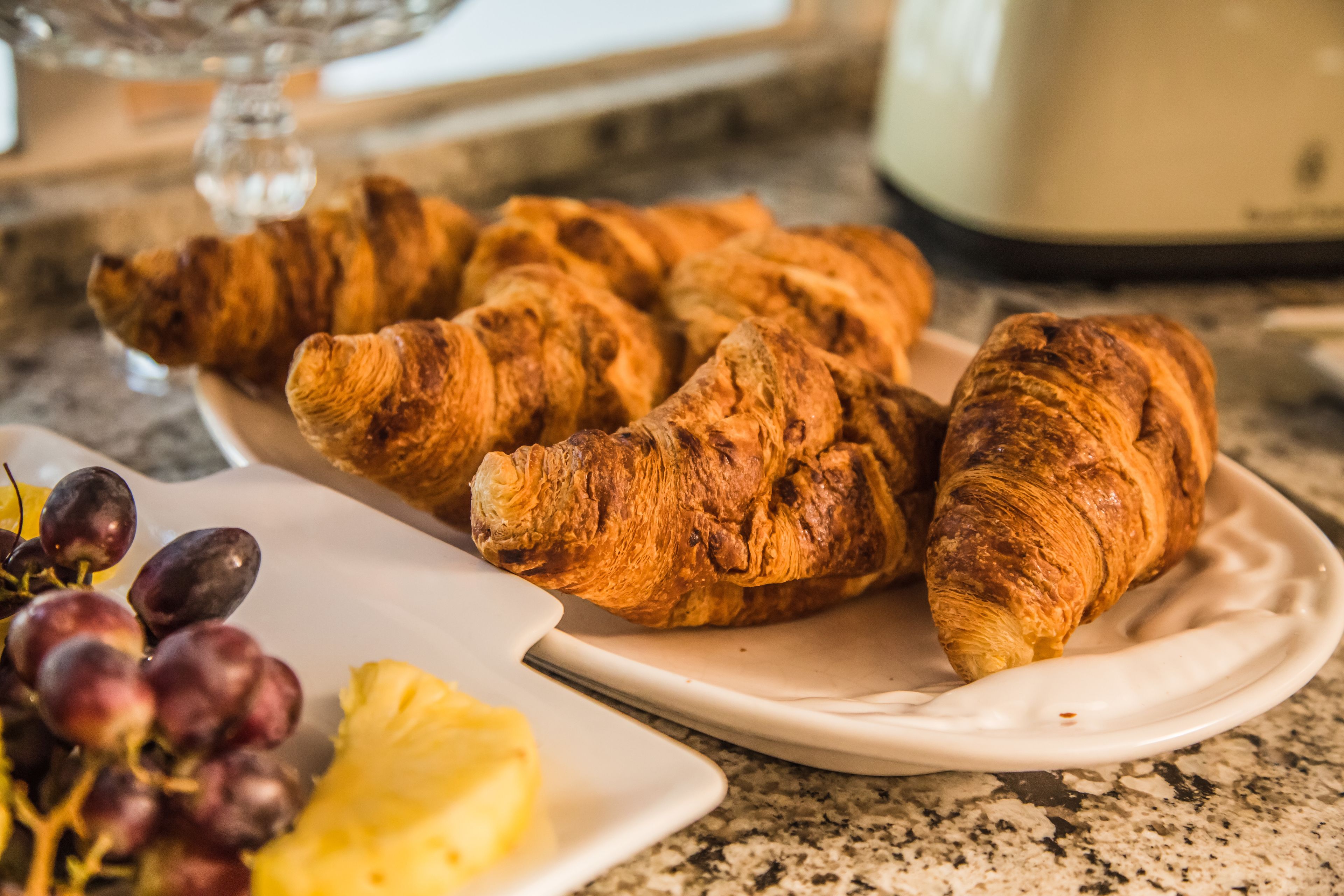 Ein Teller mit Croissants und Trauben auf einer Küchenarbeitsplatte.