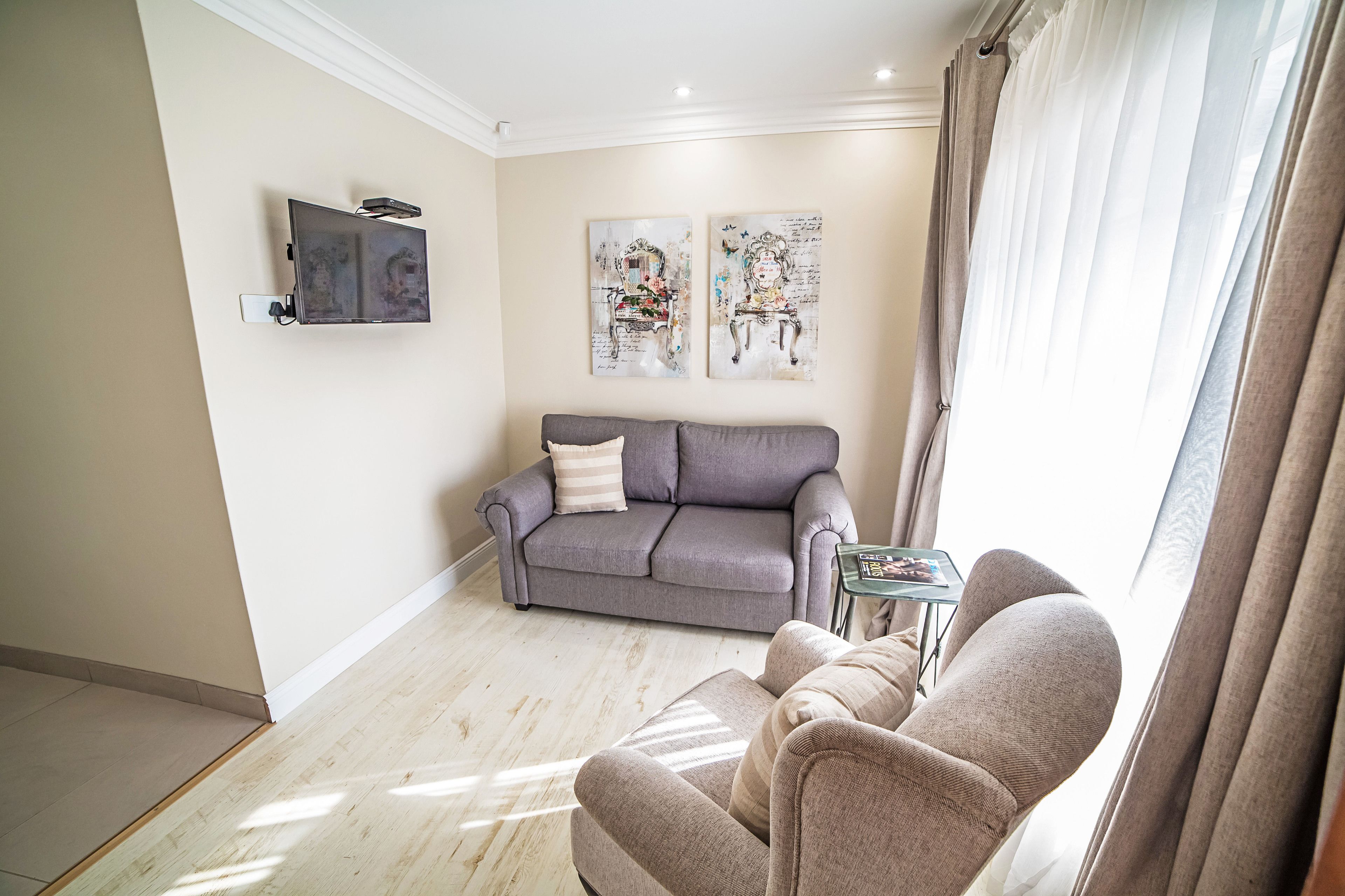 Ein Wohnzimmer mit grauem Sofa, einem kleinen Tisch und zwei an der Wand befestigten Bildern.