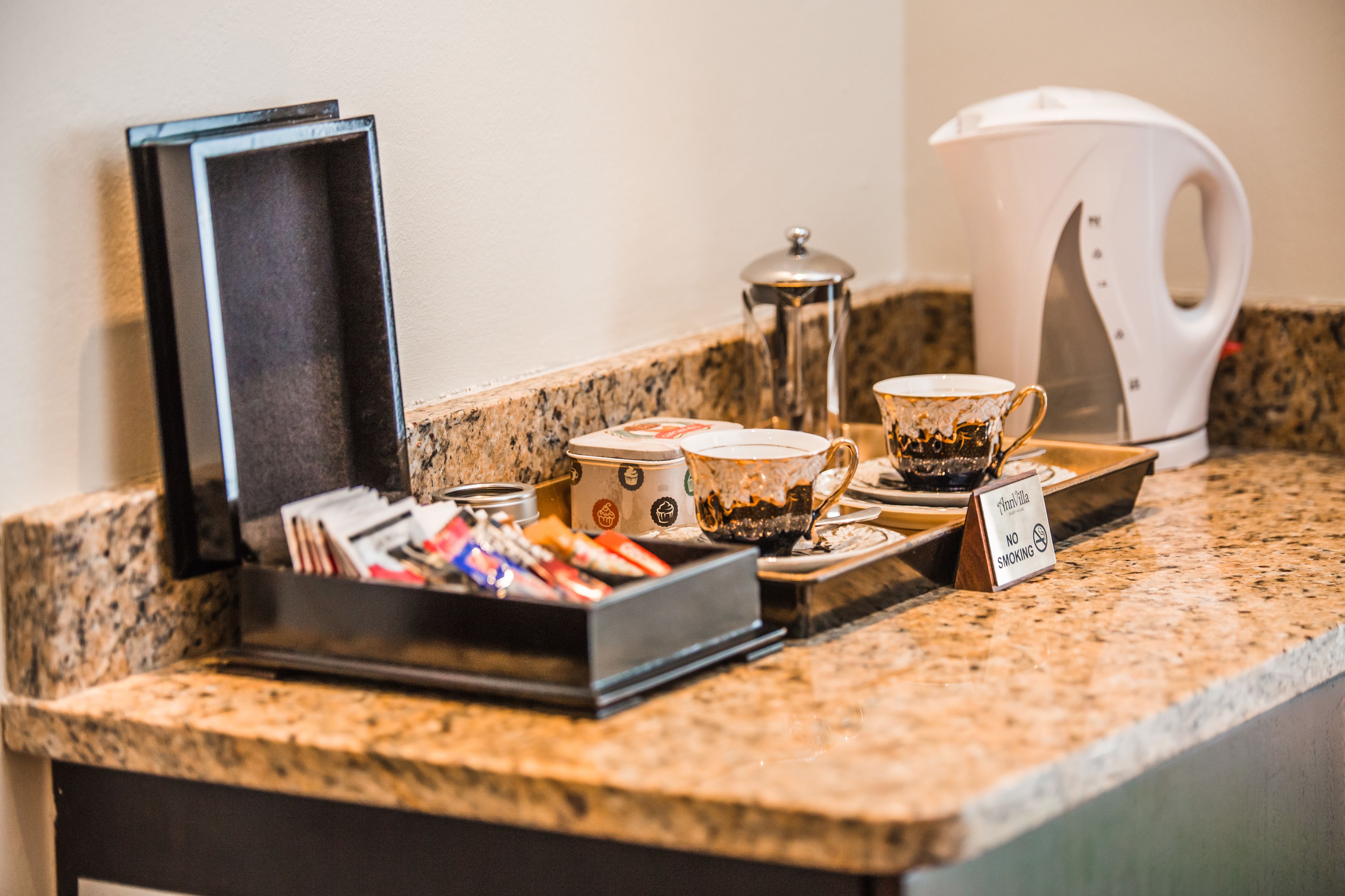 A coffee station with a coffee maker, cups, and a sign indicating no smoking.