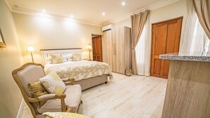 A bedroom with a bed, a chair, a desk, and a wardrobe. - AnnVilla Guesthouse (Klerksdorp)
