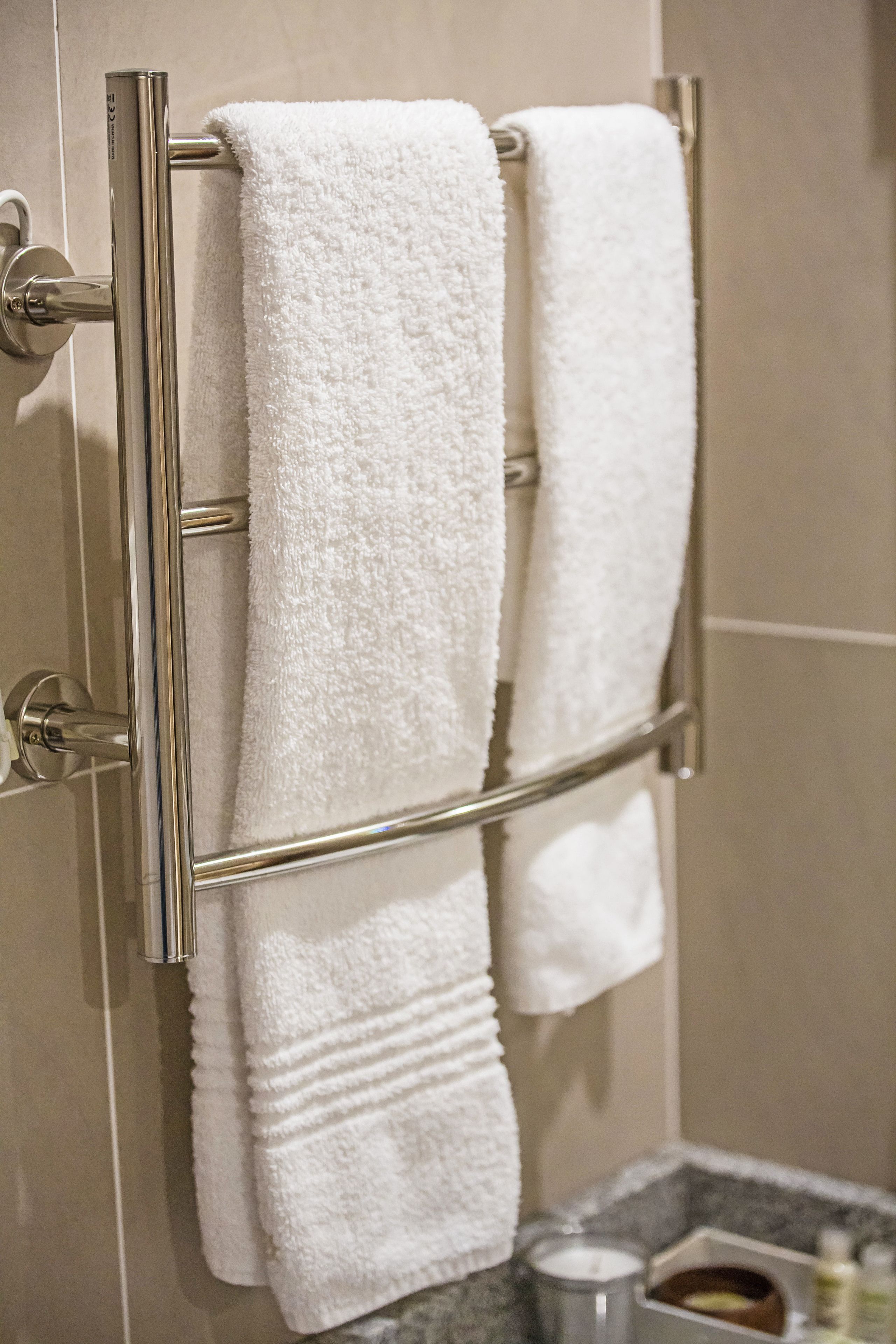 Un baño con dos toallas blancas colgadas en un perchero de metal.
