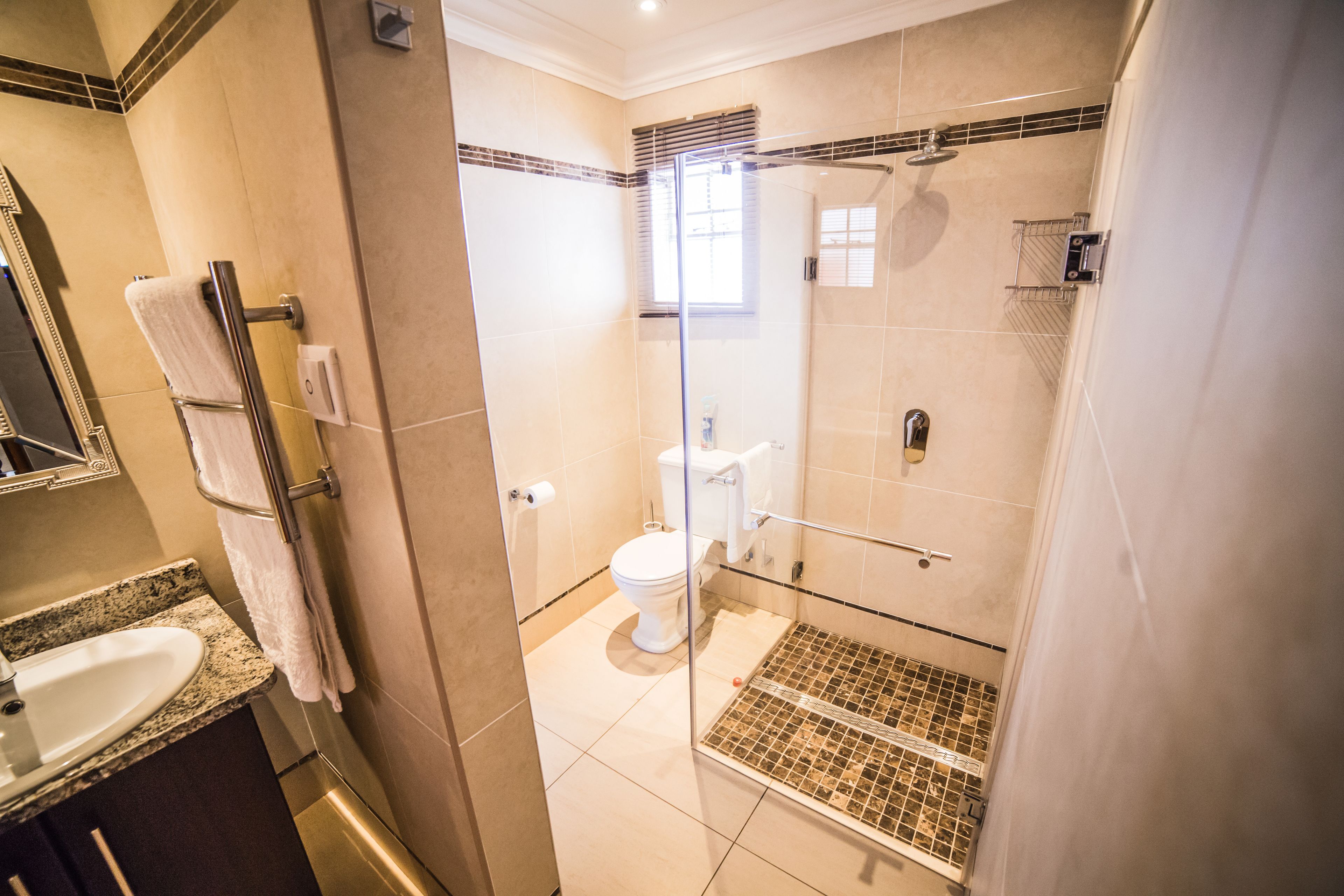 A modern bathroom with a glass-enclosed shower, a toilet, and a sink with a granite countertop.
