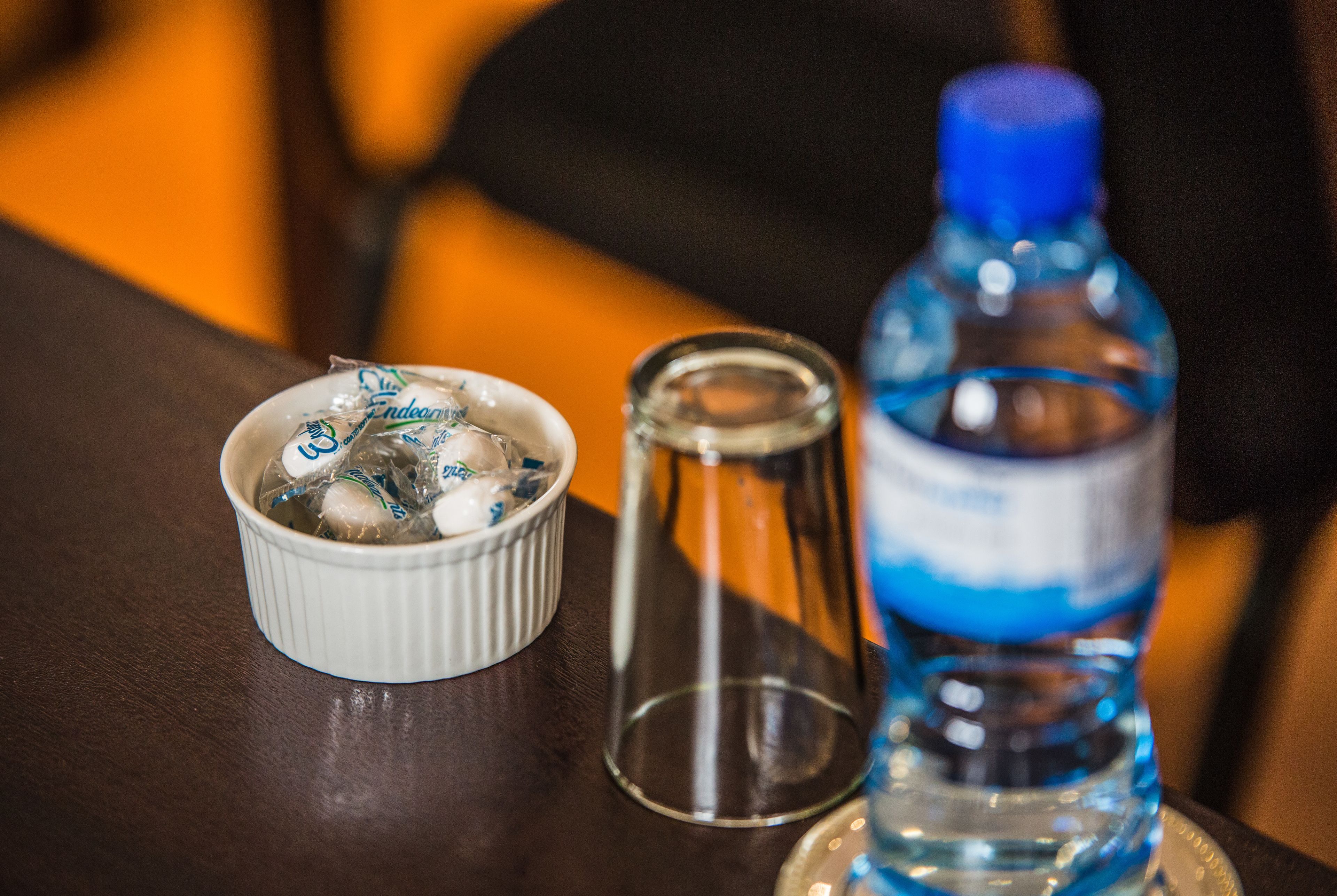 Un tazón blanco pequeño con hielo y una botella de agua sobre una mesa.