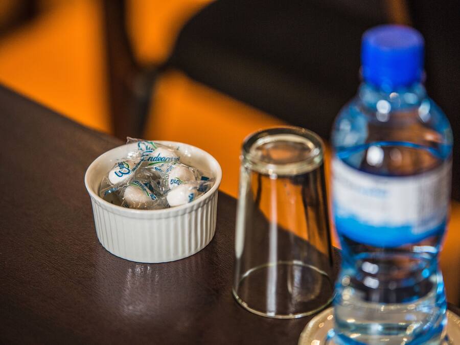 Un tazón blanco pequeño con hielo y una botella de agua sobre una mesa.