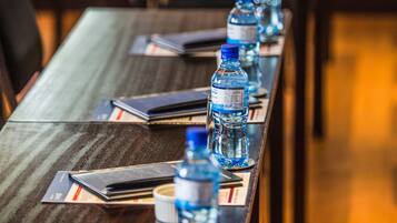 Un salón de conferencias con una larga mesa, botellas de agua y cuadernos.