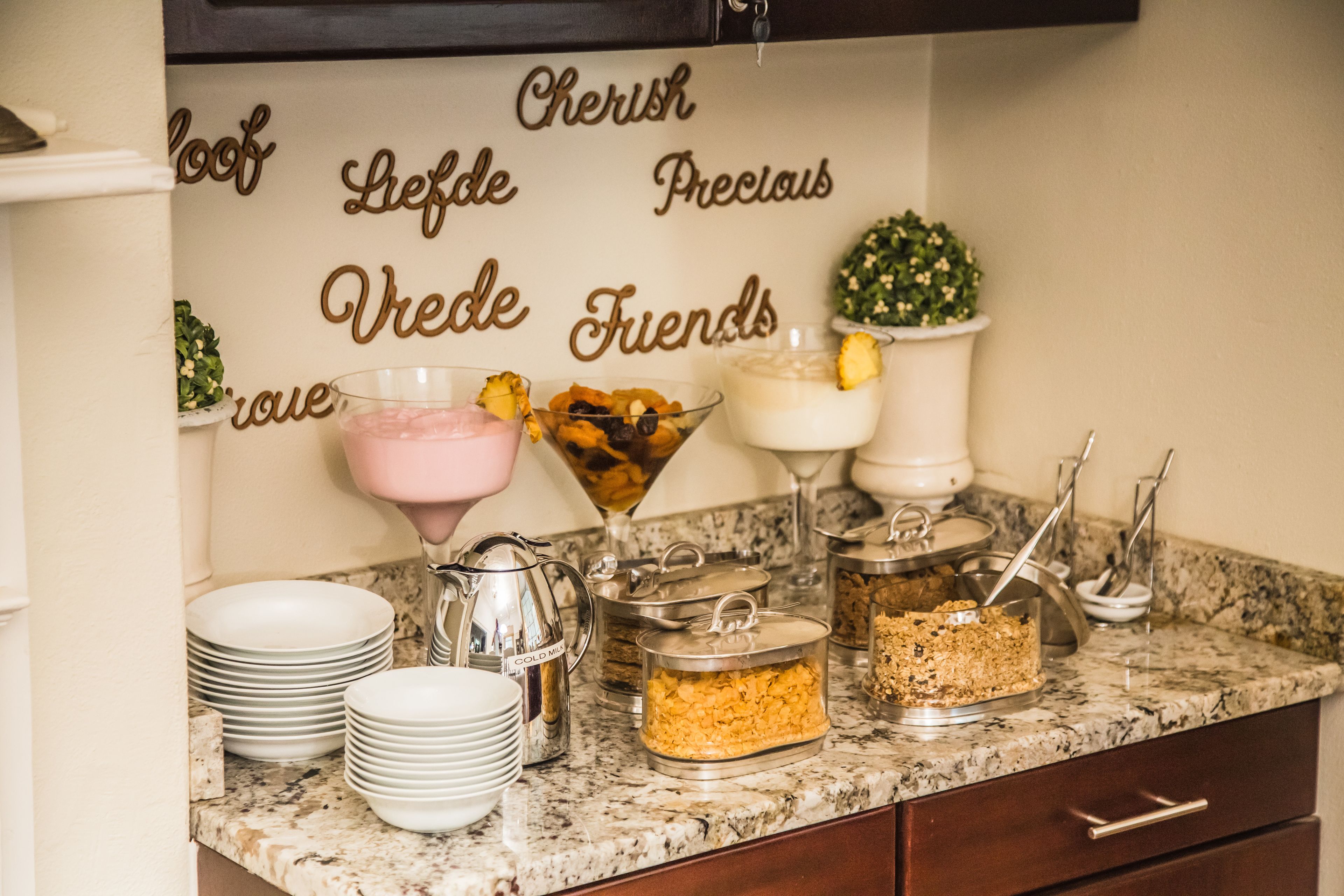 A buffet setup with various food items and a decorative wall with words.