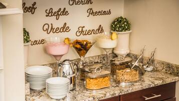 A buffet setup with various food items and a decorative wall with words.