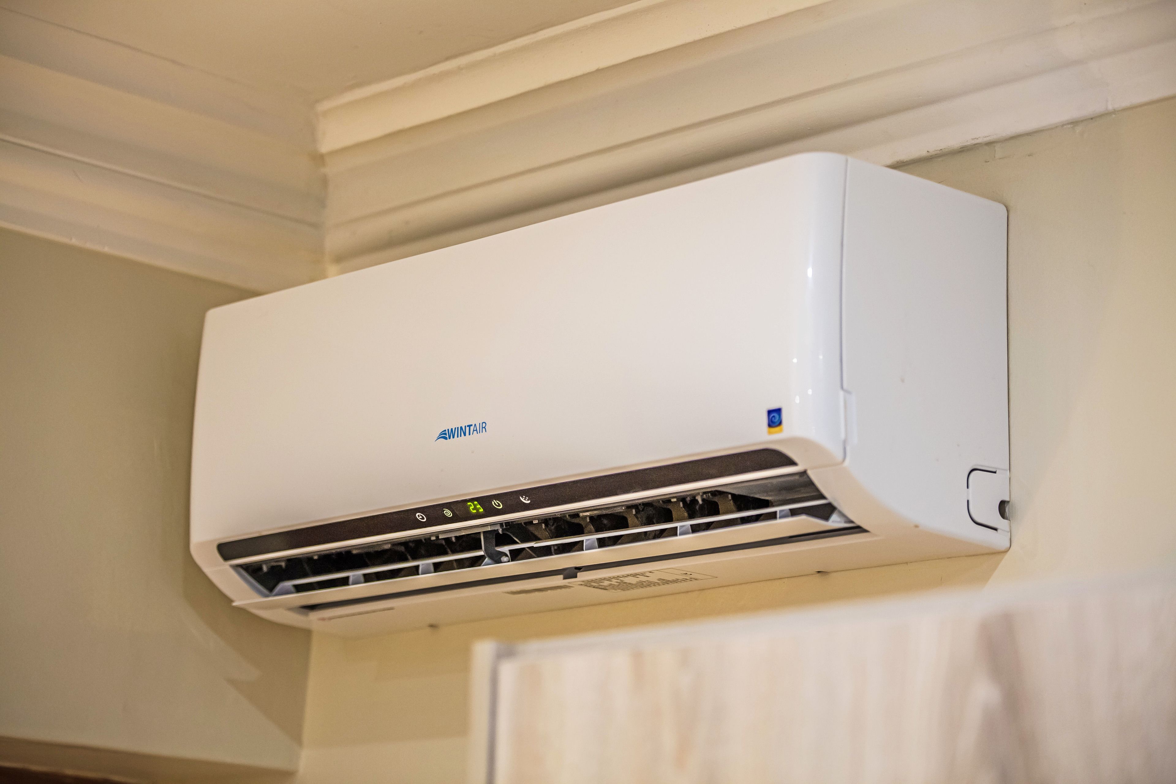A white wall-mounted air conditioning unit with a control panel and a visible brand logo.