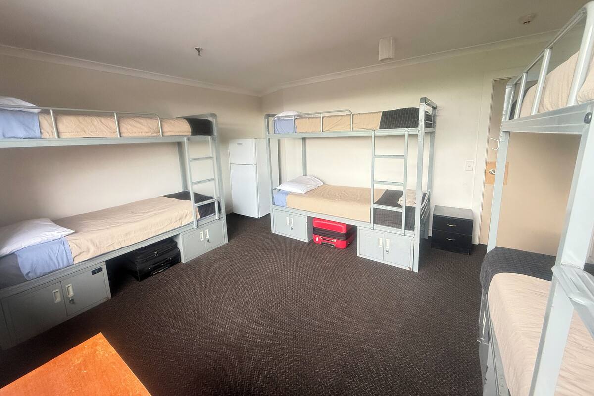 A dormitory room with bunk beds, a refrigerator, and a small table.