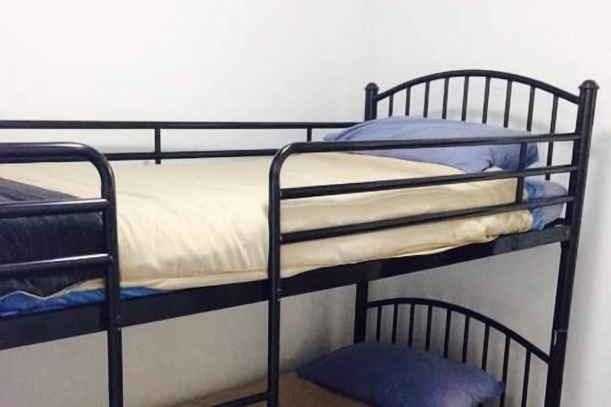 A bunk bed with two levels, each with a mattress and pillows.