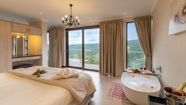 A spacious bedroom with a large bed, a bathtub, and a balcony with a scenic view. - Alkantmooi Nature Reserve Keurkloof Units (Plettenberg Bay)