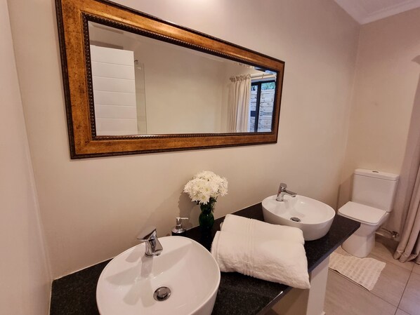 Casa de banho com duas pias, espelho e sanita.