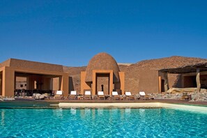 Una piscina al aire libre, sillones reclinables de piscina