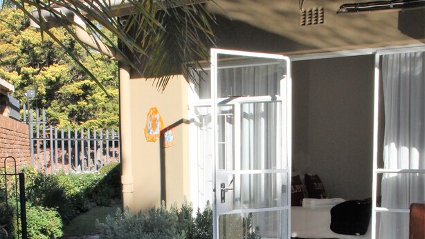 A pathway leading to a room with a bed, a window, and a door. - Memra Guest House (Ladysmith)