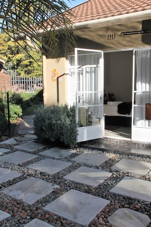 A pathway leading to a room with a bed, a window, and a door. - Memra Guest House (Ladysmith)