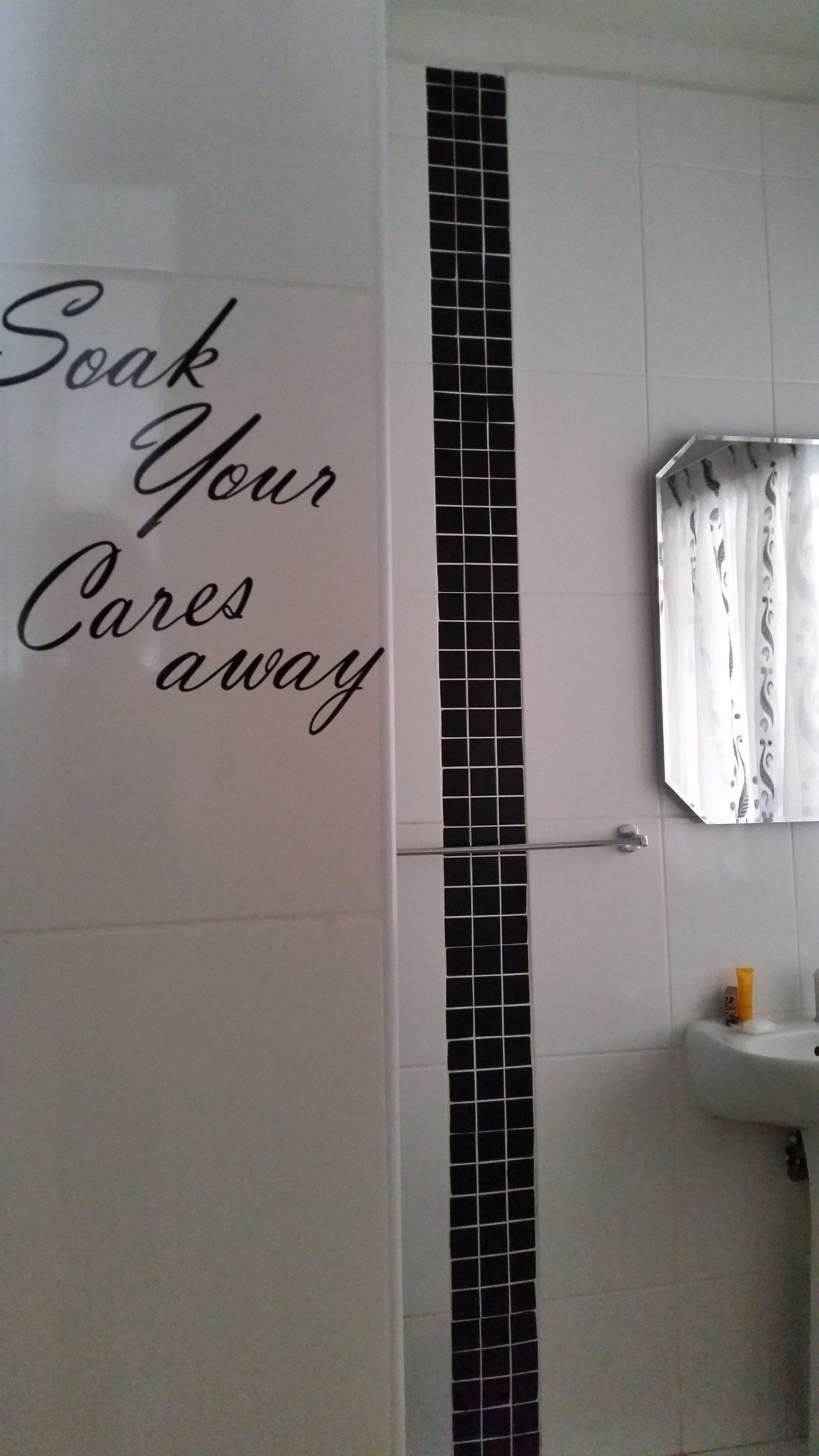 Un baño con una franja vertical de azulejos negros, un lavamanos y un espejo.