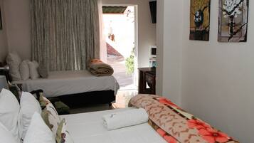 A hotel room with two beds, a TV, and artwork on the wall.