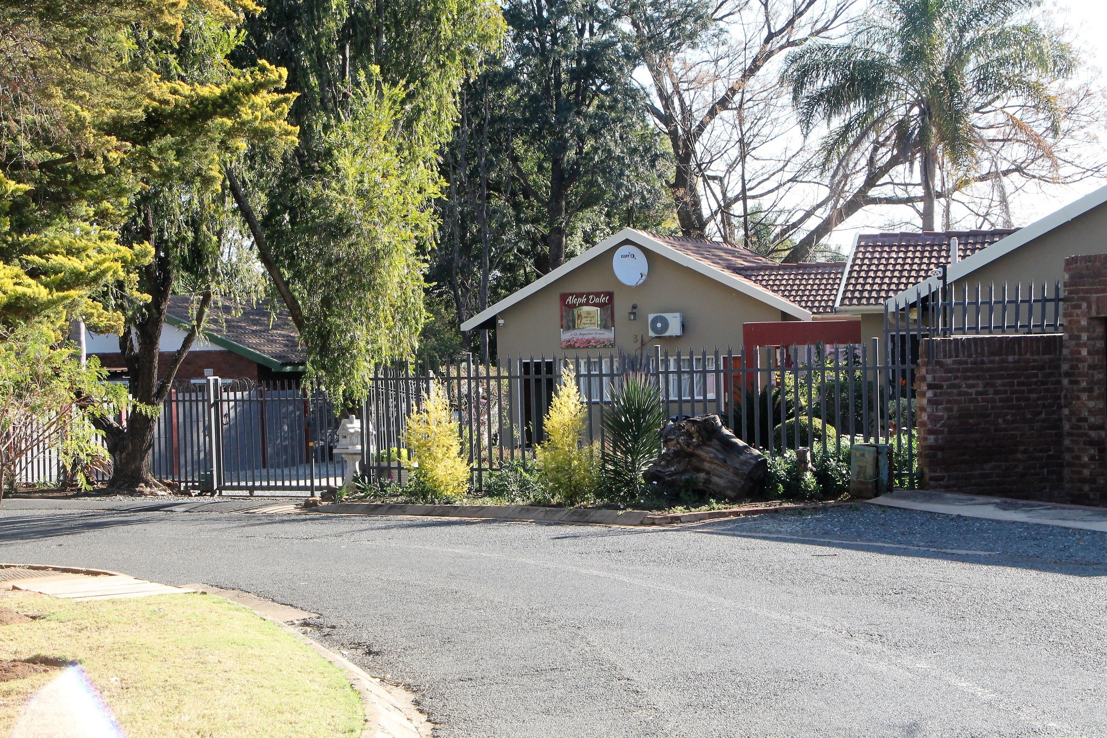 A building with a sign reading "Aloha Deli" and a fenced driveway.