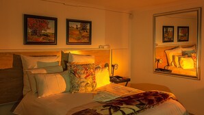 A neatly made bed with multiple pillows and a blanket, a bedside table with a lamp, and two framed pictures on the wall. - Memra Guest House (Ladysmith)