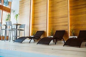 Un área de piscina interior moderna con sillones de descanso y una mesa.
