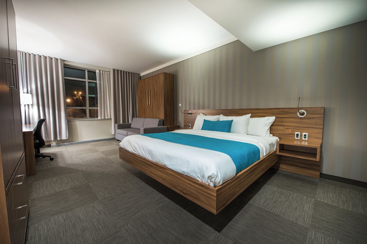 Una habitación de hotel moderna con una cama grande, un escritorio y un armario.