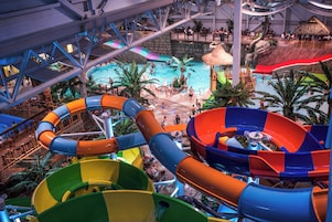 Parque acuático interior con múltiples toboganes y una zona de piscina central.