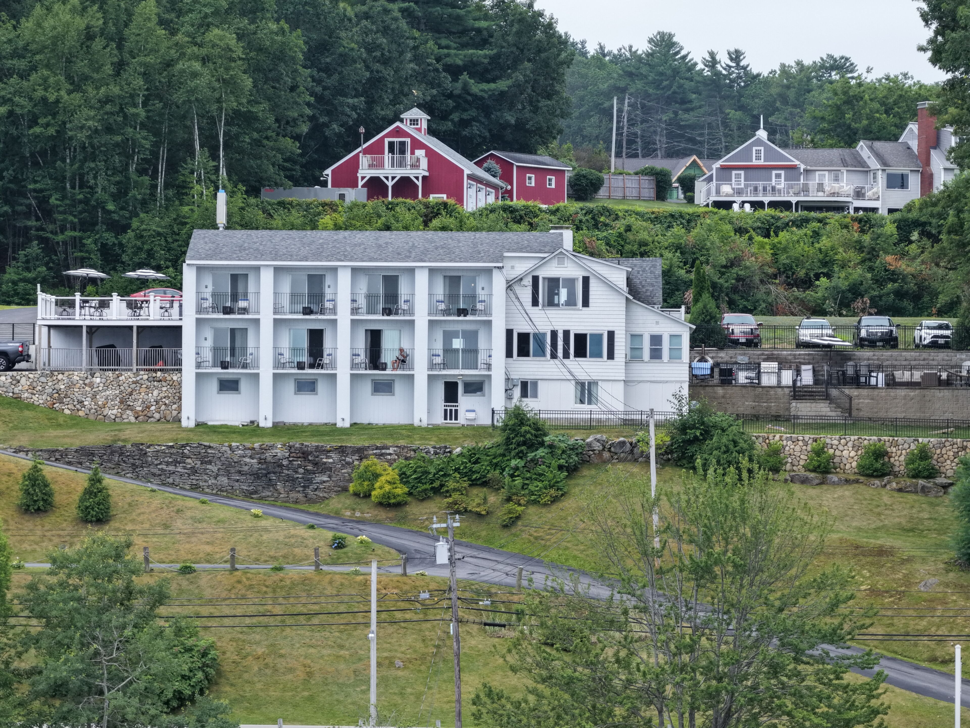 A multi-story hotel with balconies, a stone retaining wall, and a parking area.