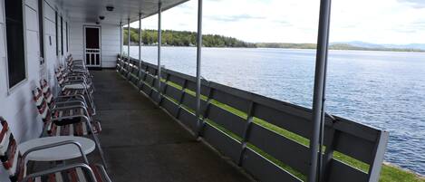 Una terraza techada con filas de sillas mirando hacia un lago.
