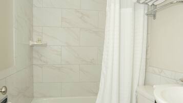 A modern bathroom with a bathtub, toilet, and a shower curtain.