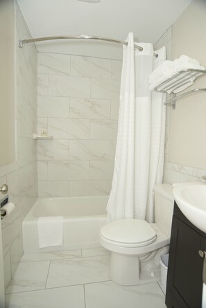 A modern bathroom with a bathtub, toilet, and a shower curtain.