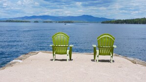 Two green Adirondack chairs facing a lake with mountains in the background. - Belknap Point Inn (Gilford)