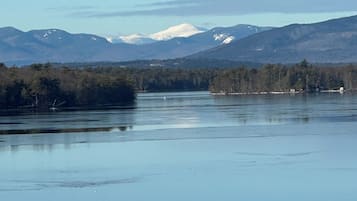 Um lago calmo com montanhas ao fundo e uma linha de costa arborizada.