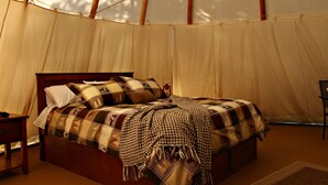 Una carpa con una cama, una mesita de noche y una silla.