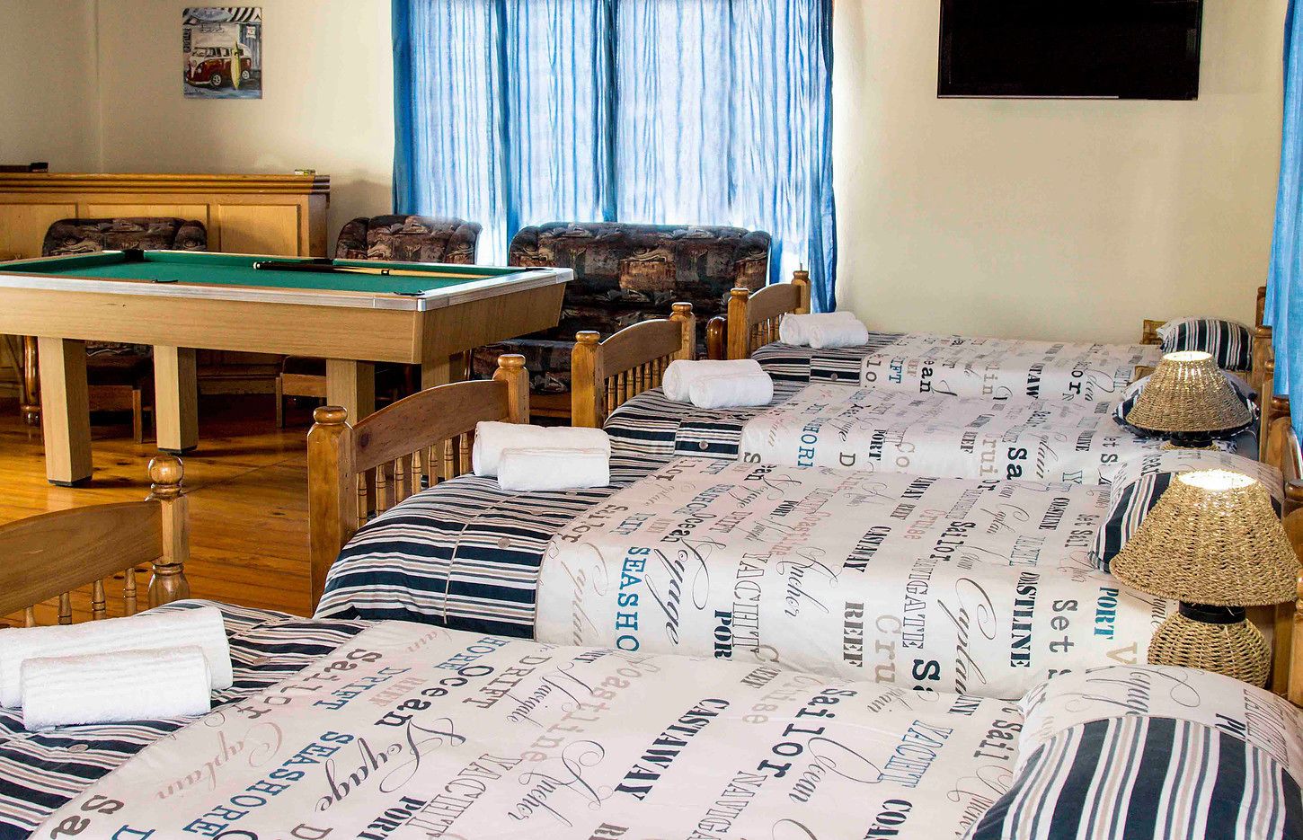 A hotel room with a pool table, a sofa, and a bed with a striped bedspread.