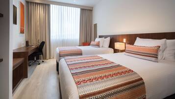 Habitación de hotel con dos camas, un escritorio y una silla.