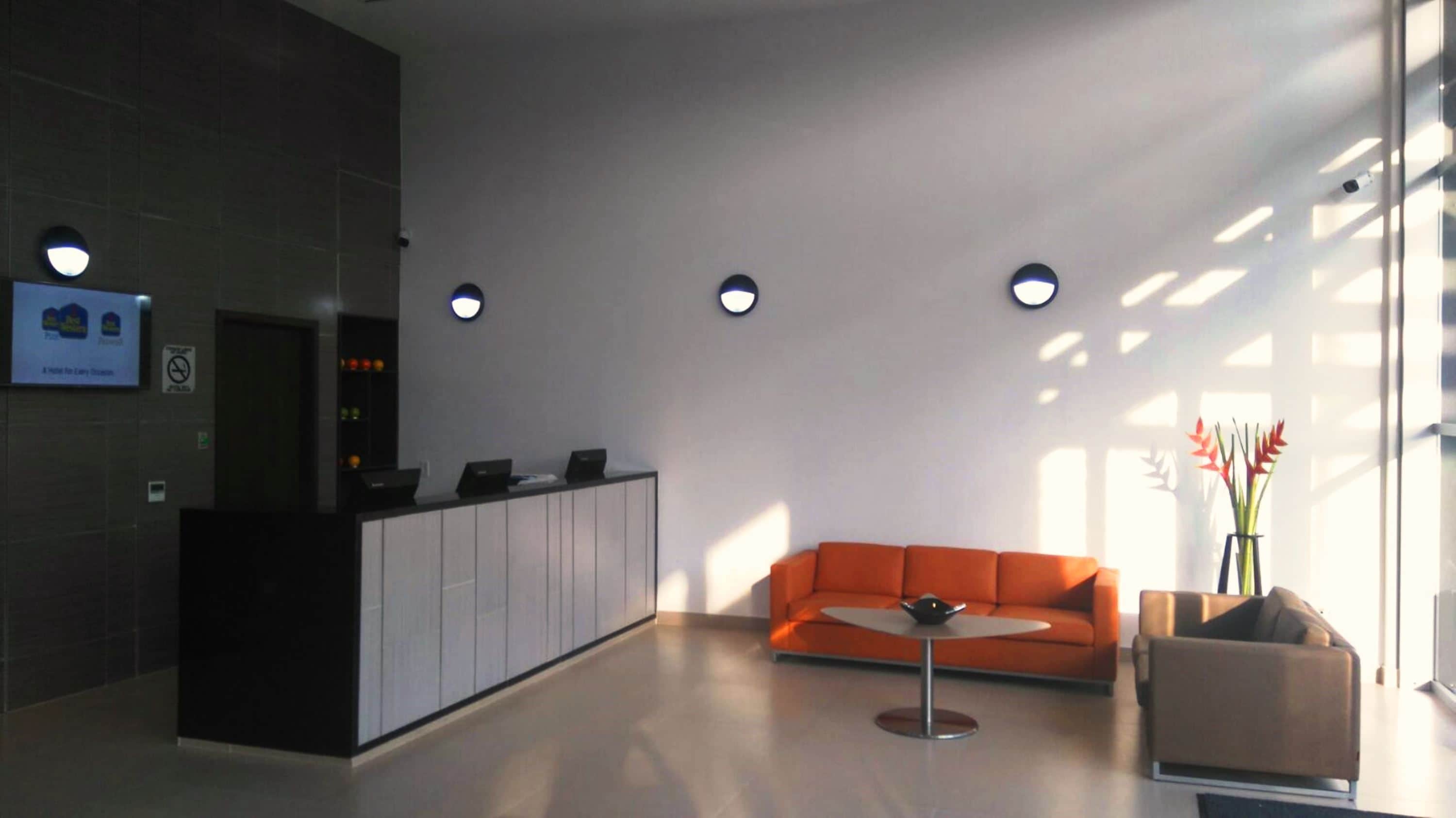 Een moderne lobby met een receptiebalie, een bank en een klein tafeltje.