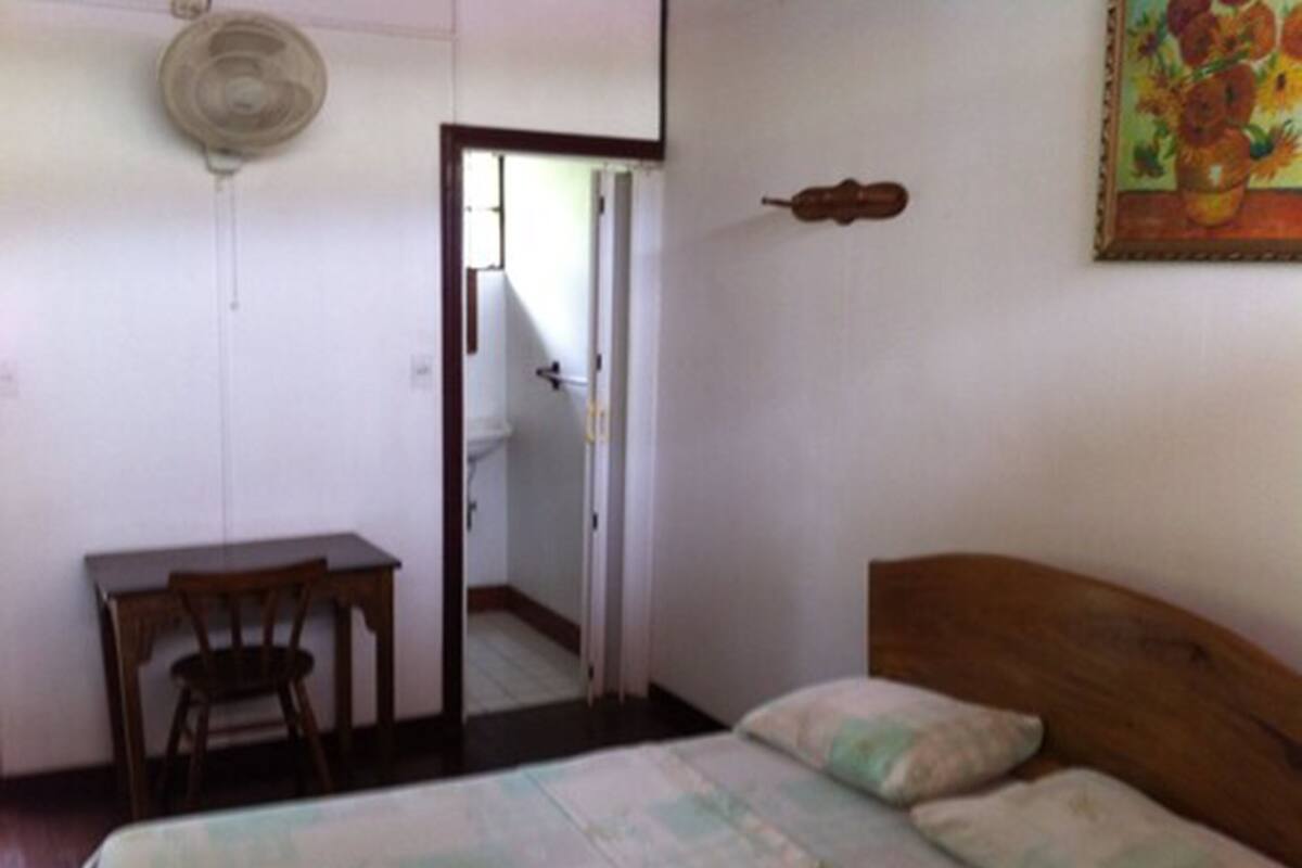 Ein Schlafzimmer mit Bett, Schreibtisch und Stuhl. Eine Tür führt zu einem Badezimmer.