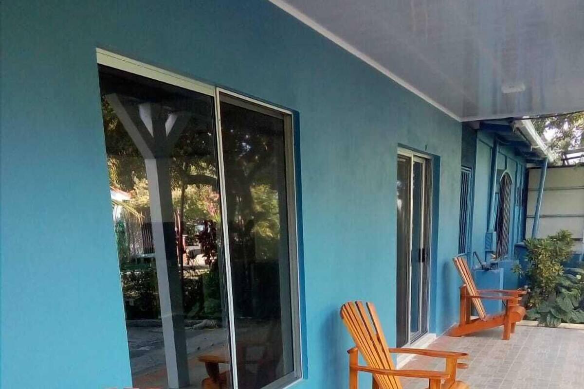 Ein überdachter Außenbereich mit Holzstühlen und einem großen Fenster.
