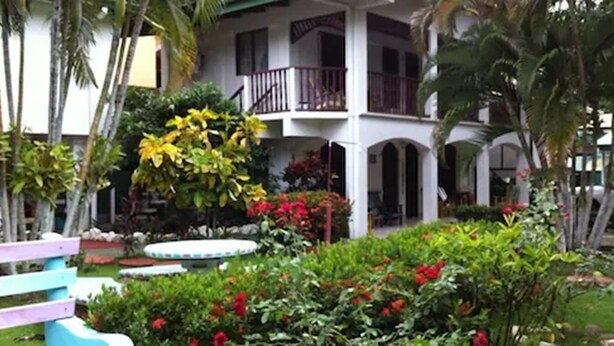 A hotel with a covered outdoor area, a pool, and lush greenery. - Cabinas Marielos (Tamarindo)